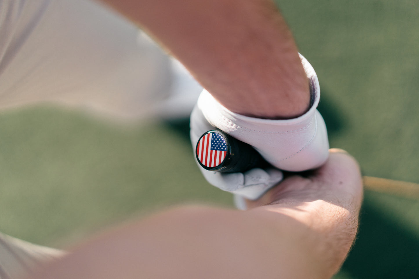 Close-up of a person holding a golf club with a flag design on the grip.