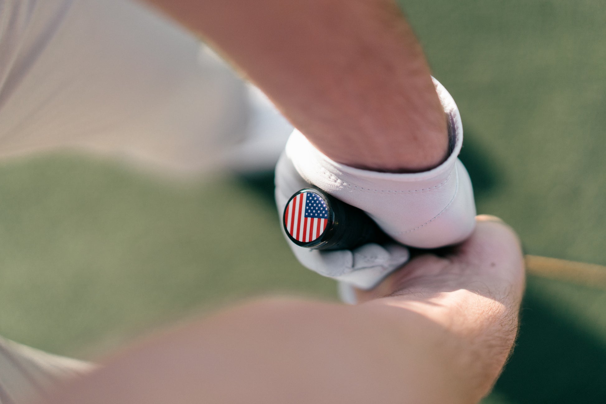 Close-up of a person holding a golf club with a flag design on the grip.